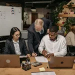 Tim profesional bekerja bersama di kantor modern dengan laptop dalam suasana kolaboratif